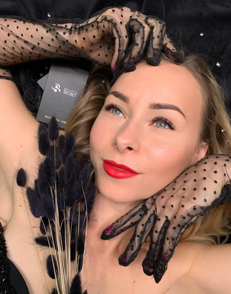 Glamúros portré műszempillás nőről, fekete pöttyös fátyolkesztyűben, Beauty’s Secret feliratú kártyával
