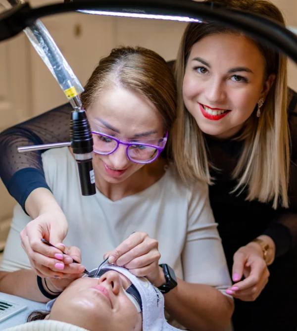 Egy oktató UV-LED lámpánál mutatja a szempillaépítést egy fekvő modellen.