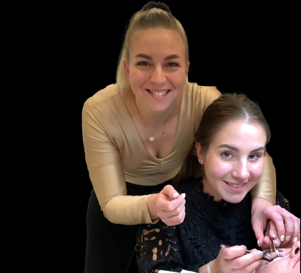 Szempilla-stylist csipesszel dolgozik egy vendég szemén, oktatója mellette áll.